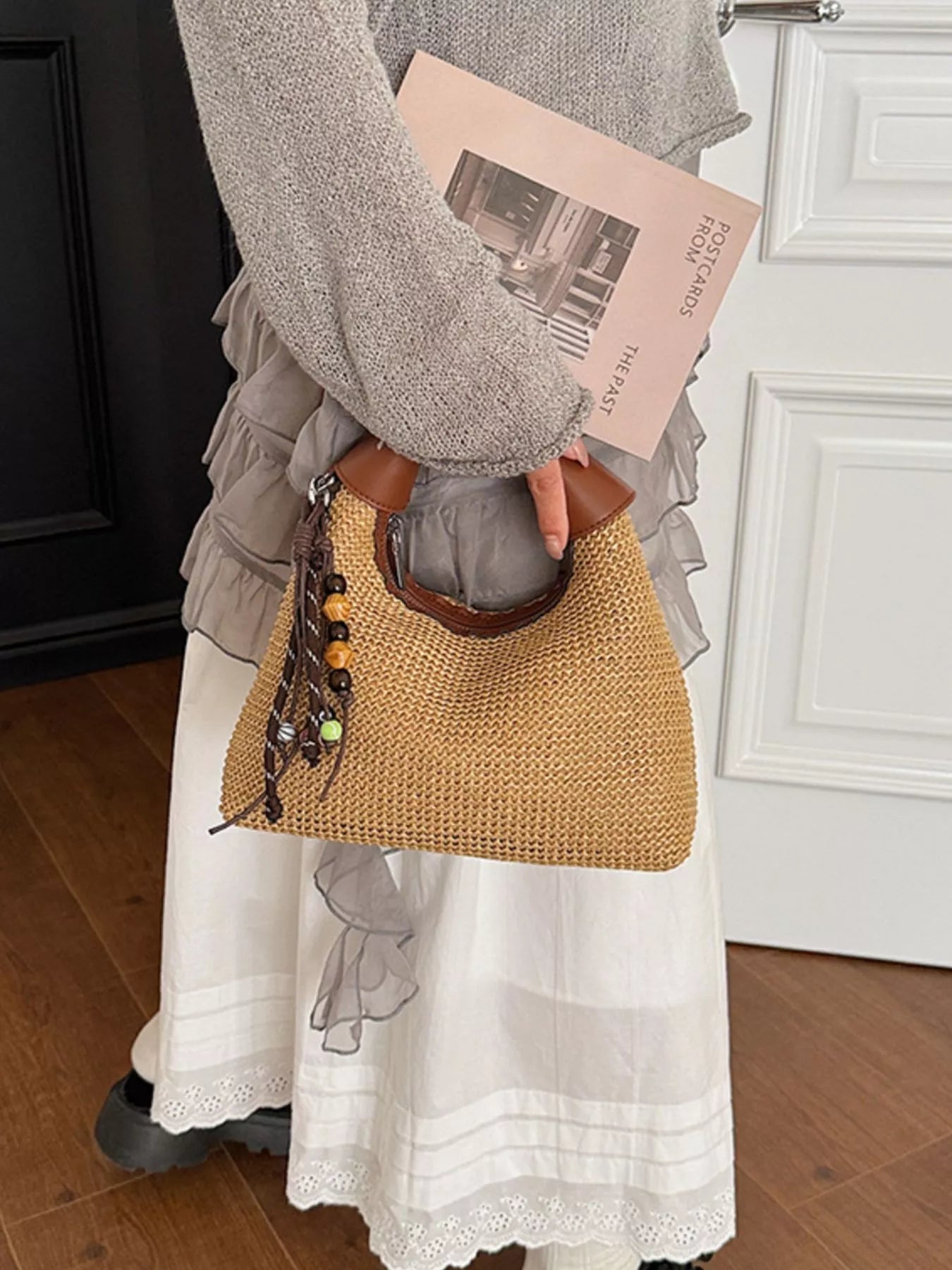 Straw crossbody bag with brown leather handle, beaded tassel detail, top opening with trim