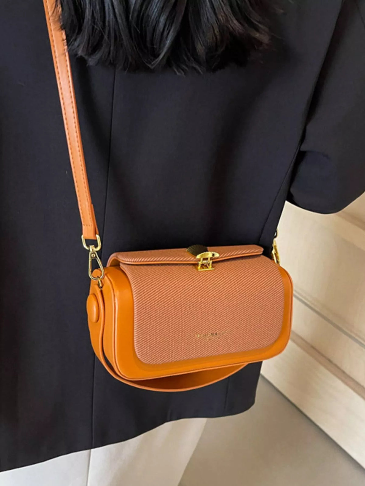 Brown and tan crossbody bag with flap, gold-tone hardware, and adjustable strap