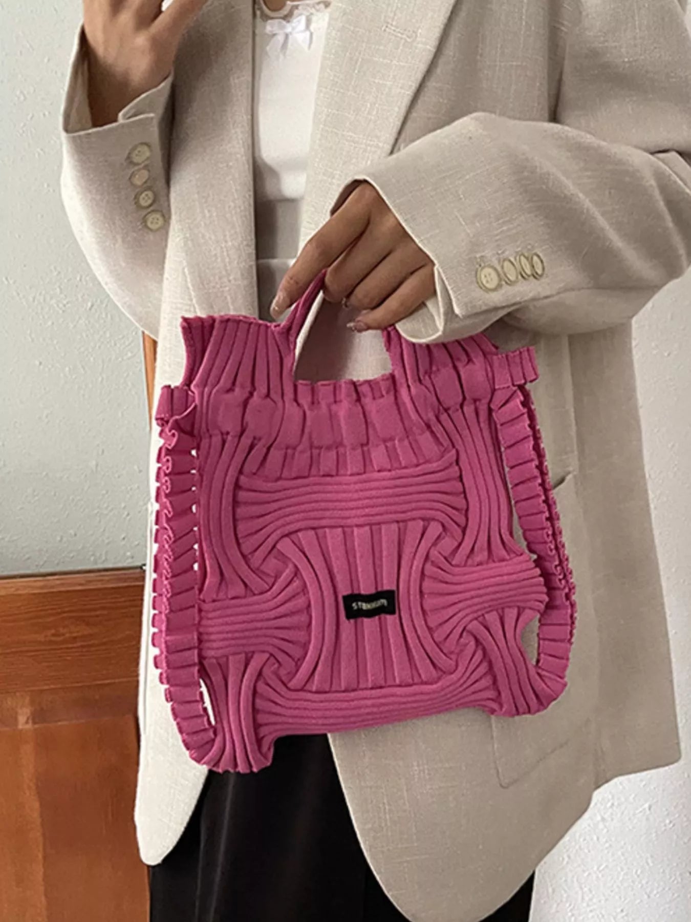 Rose red knitted backpack bag with ruffled knit edges and black logo patch