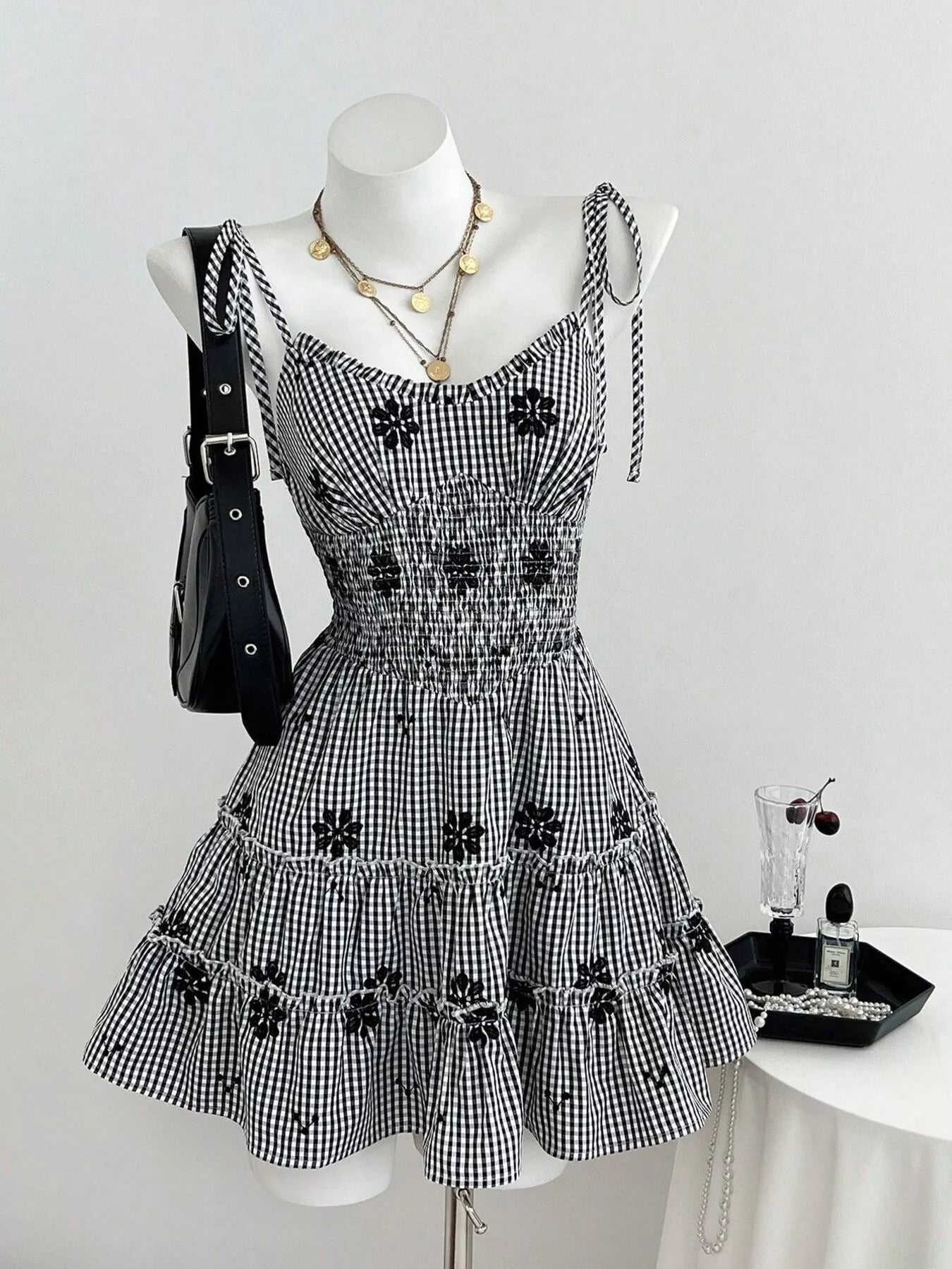 Black gingham tiered mini dress with dark floral appliques and ruched bodice