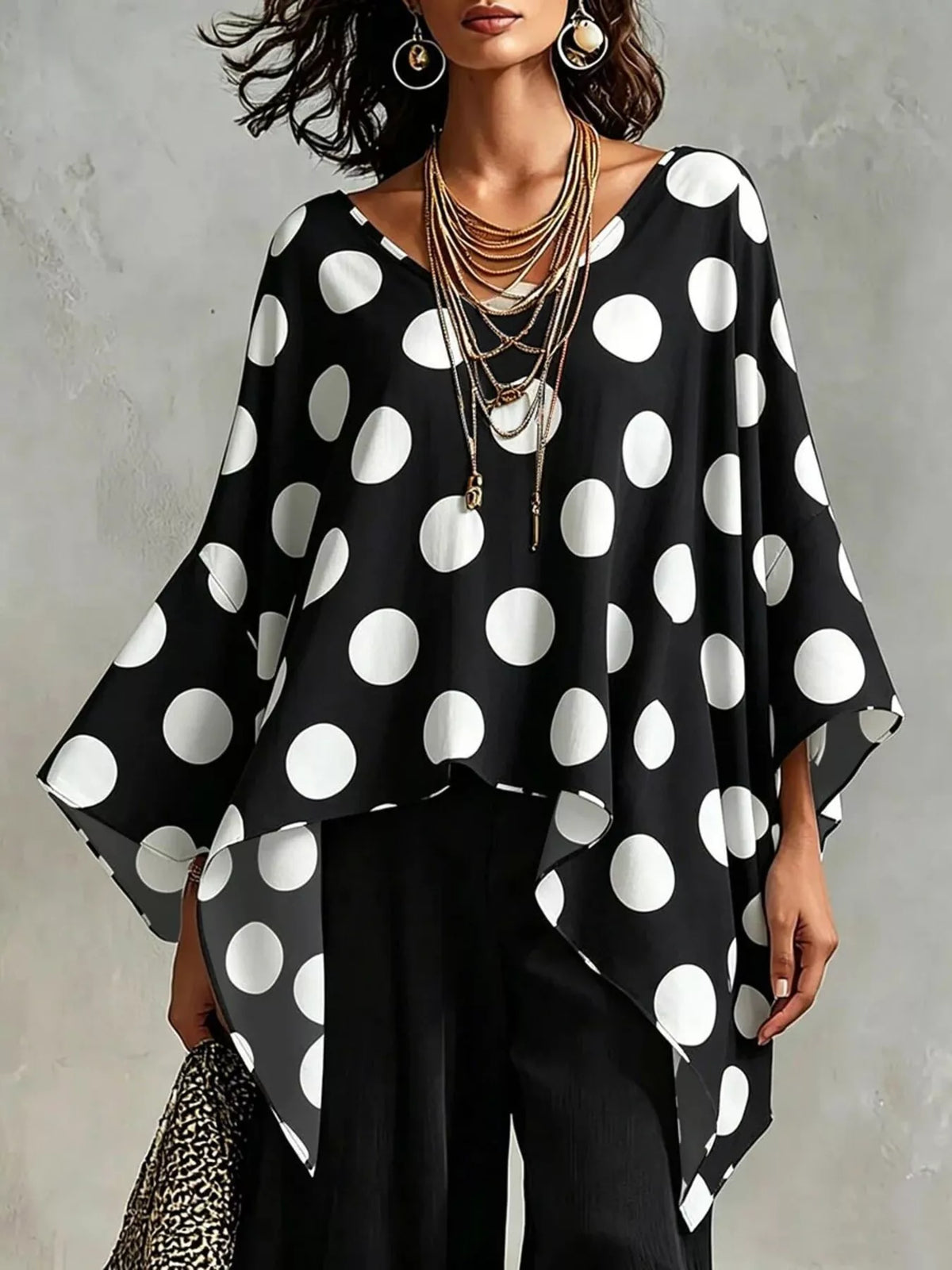 Black polka dot asymmetrical hem blouse with batwing sleeves and V-neckline.