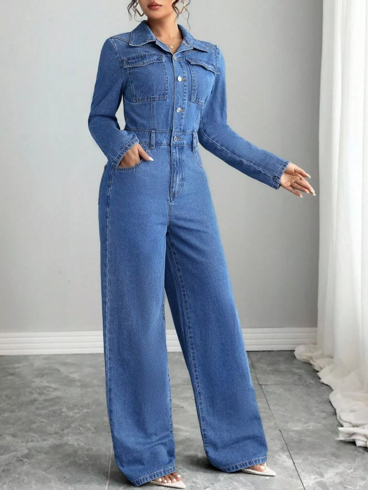 Blue denim long-sleeve button-front jumpsuit with front pockets and wide straight legs