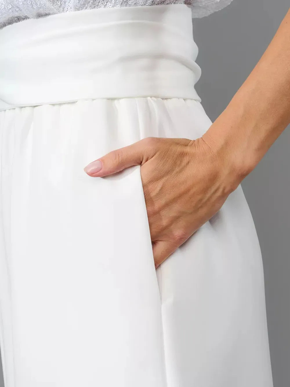 White wide-leg jumpsuit close-up of elastic gathered waist and draped front.