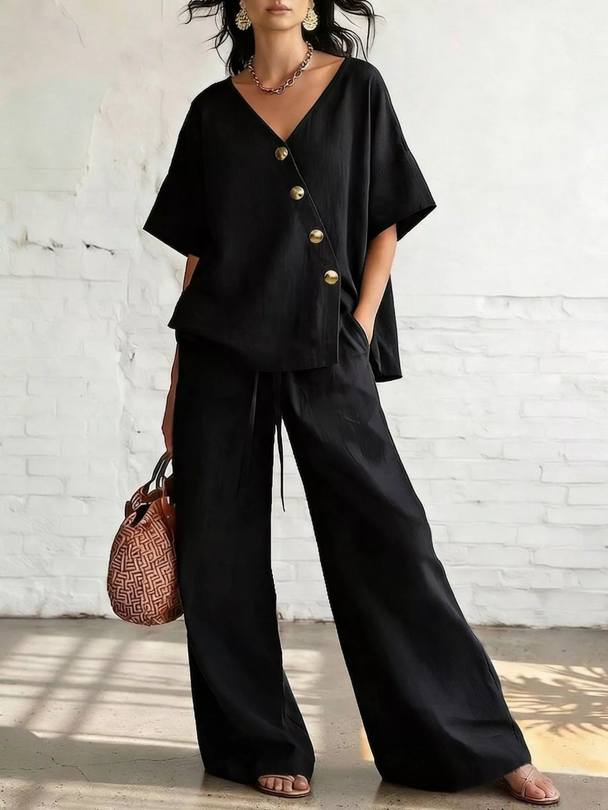 Black surplice half-sleeve top with gold buttons and wide-leg pants