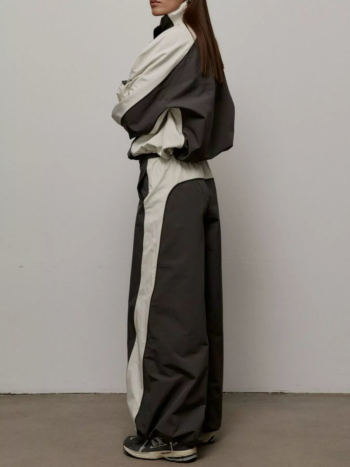 Color-block zip-up jacket and pants set shown in side view, black and light color blocks.