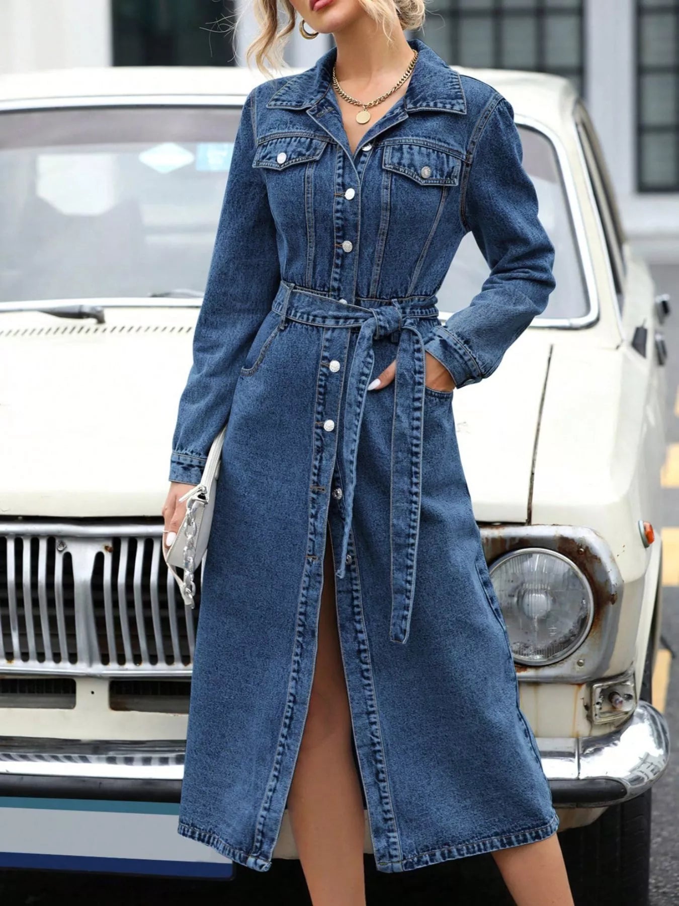 Blue denim long-sleeve belted dress with front button placket and wrap waist tie.