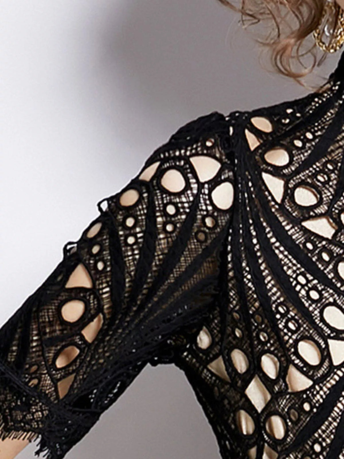 Close-up of black lace short sleeves with circular cutout patterns and scalloped edge