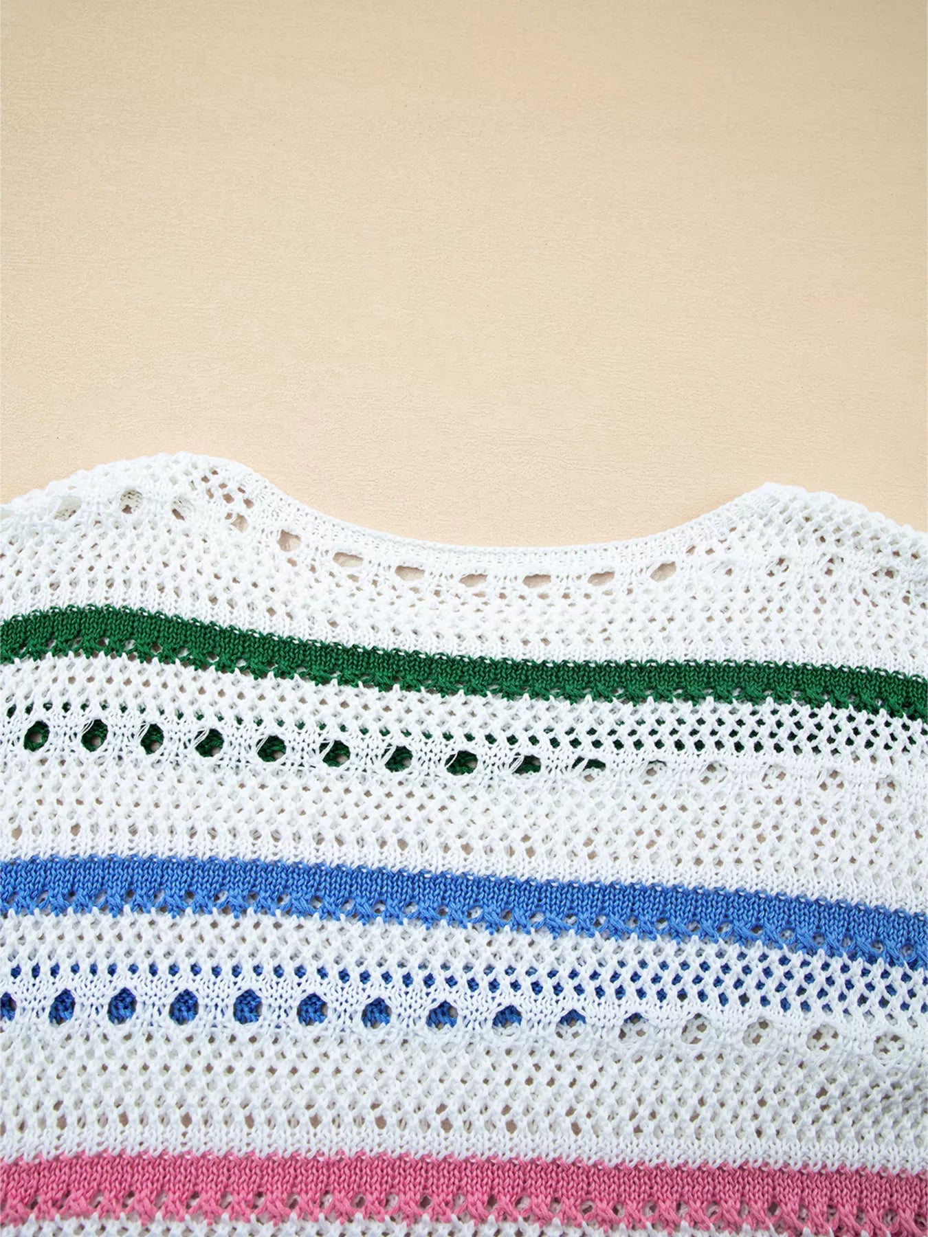 White pointelle knit sweater close-up with green, blue, and pink stripe bands
