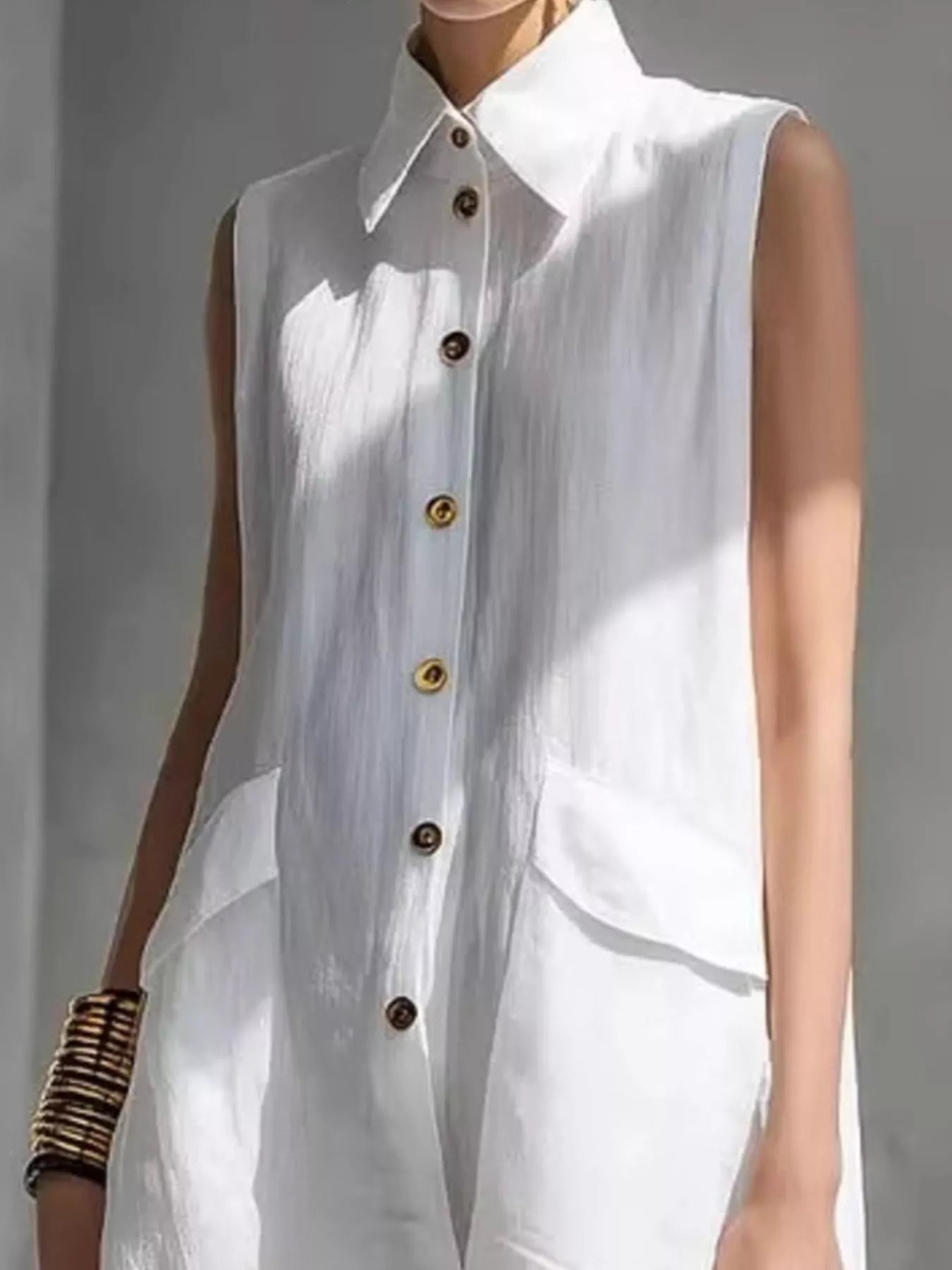 White sleeveless button-front dress with pointed collar and chest-to-hem button placket