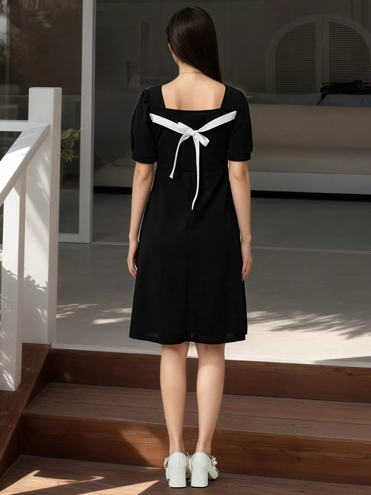 Black mini dress with bow-tied back and short puff sleeves, square neckline