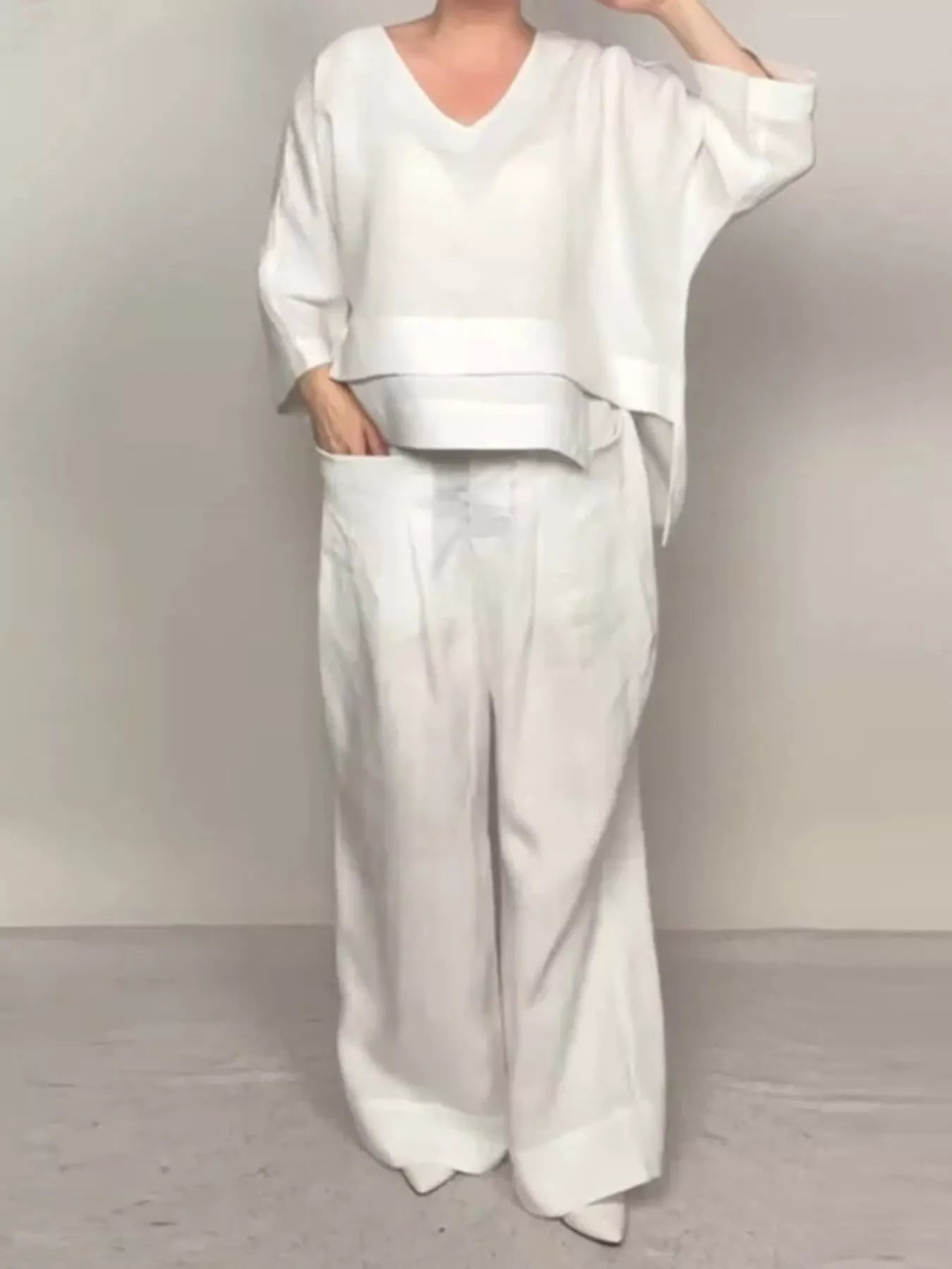 White V-neck long sleeve top and wide-leg pants set with draped overlay hem.