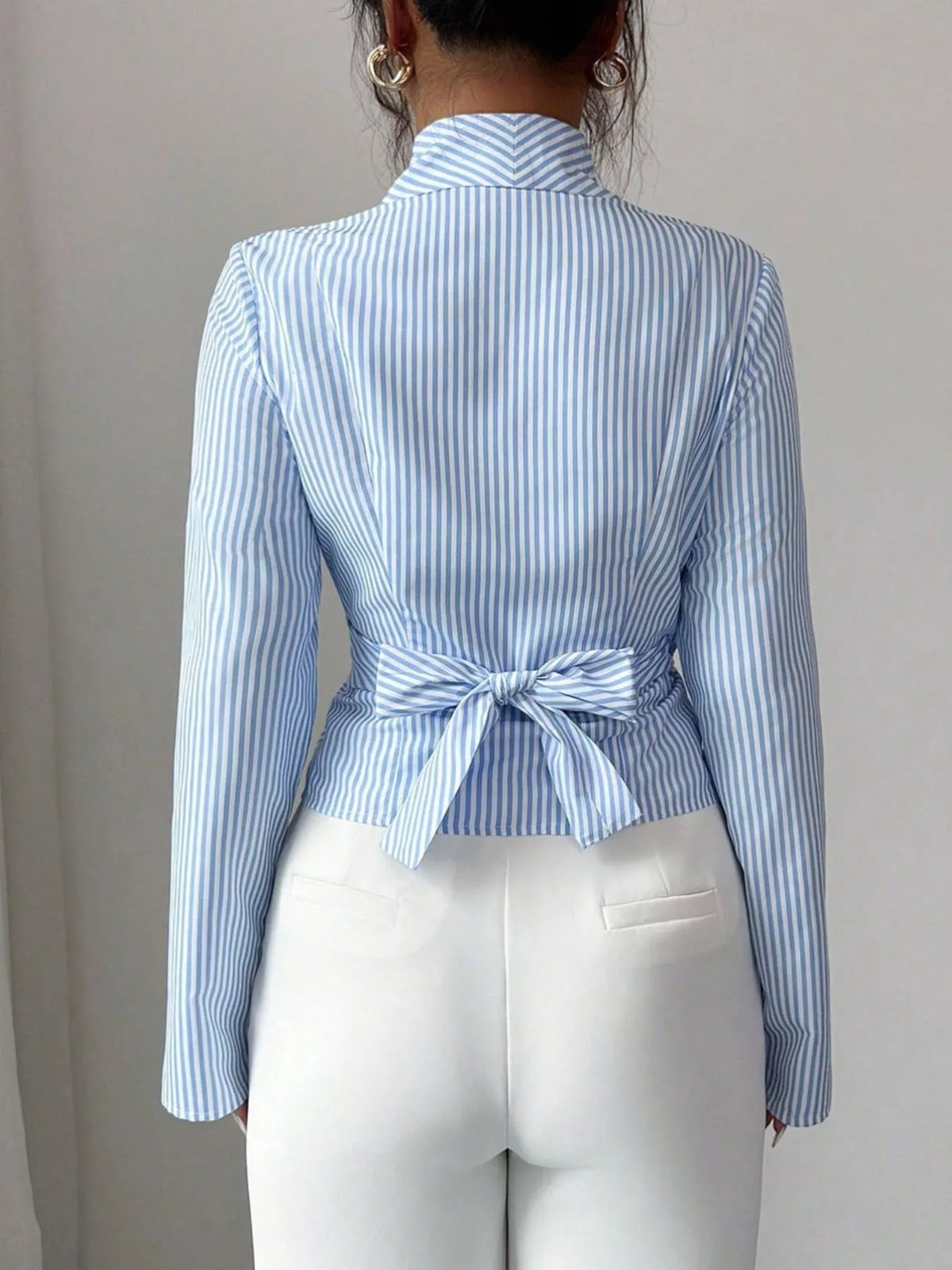 Blue striped long sleeve wrap blouse, back view with tied waist peplum