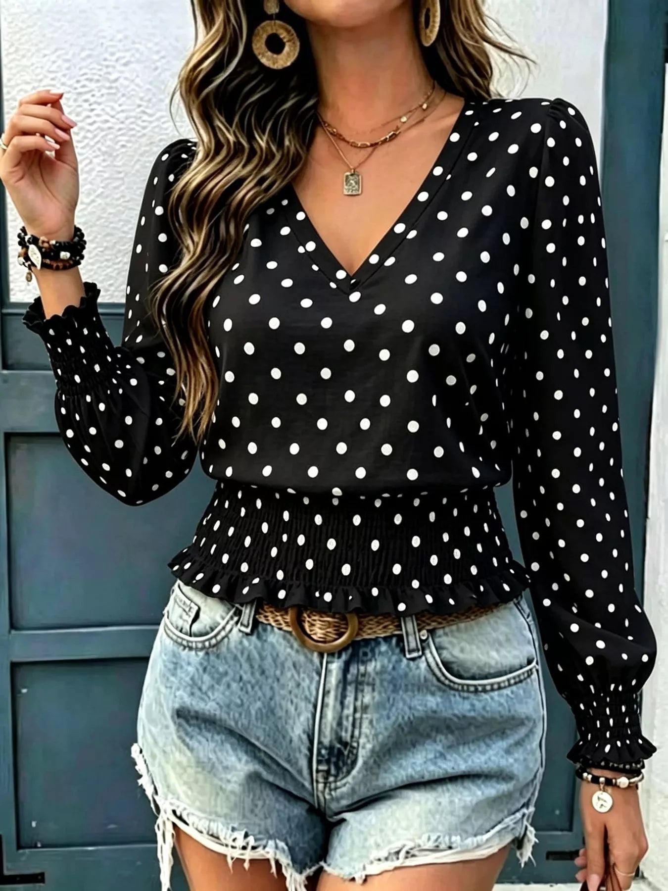 Black polka dot V-neck smocked blouse with long sleeves and gathered ruffle waist