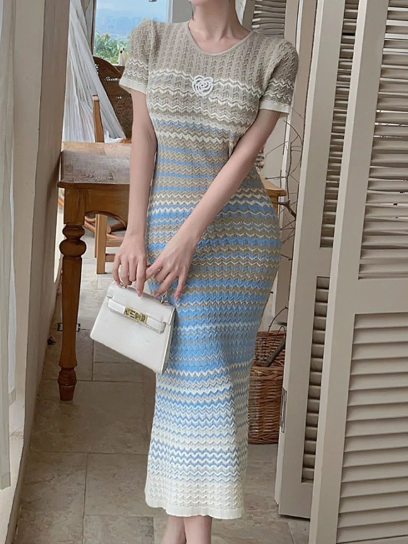 Light blue knit striped midi dress with short sleeves, round neck, and chest rosette
