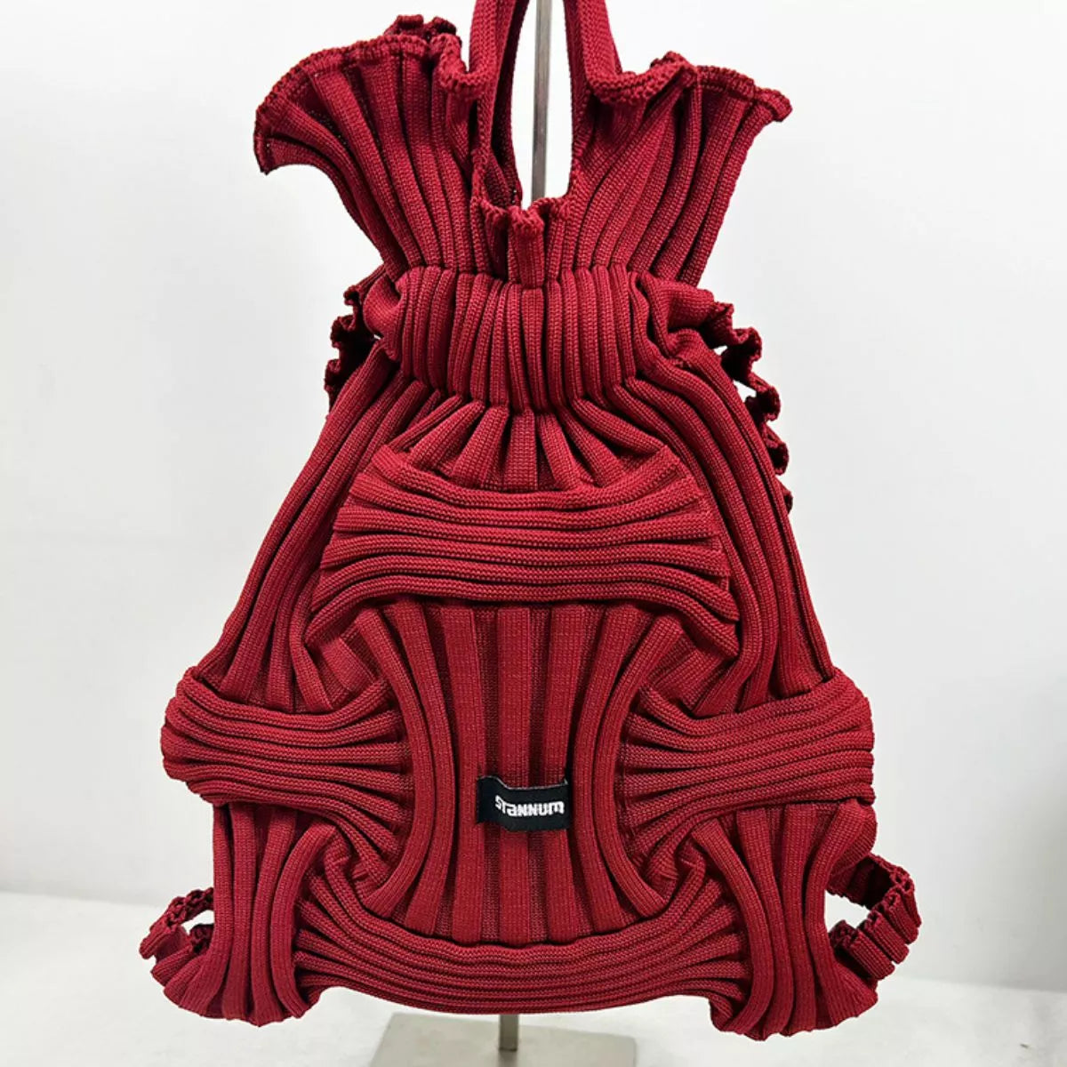 Burgundy textured knit backpack with ruffled panels, top handles, front patch logo