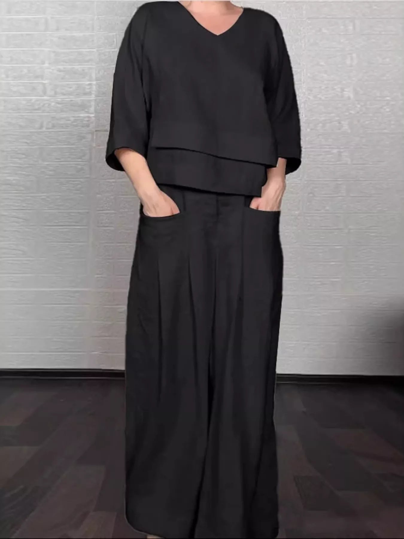 Black V-neck long sleeve top and wide-leg pants set with draped overlay hem.