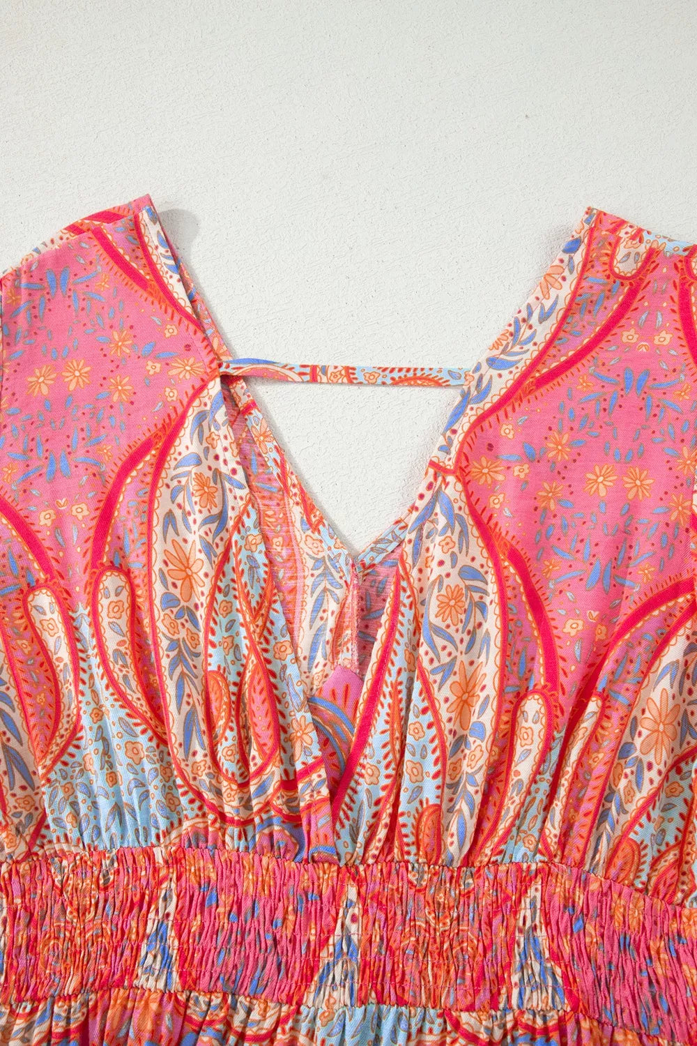 Burnt coral paisley dress neckline close-up with V-back cutout and ruffled shoulders
