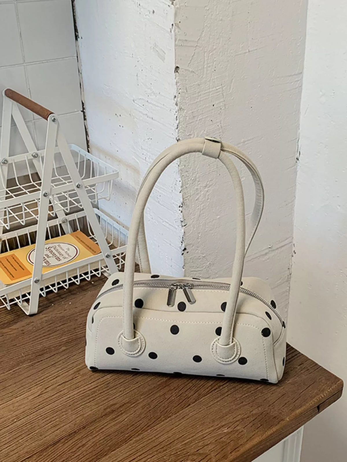 Off-white polka dot shoulder bag on a wooden surface with curved top handles