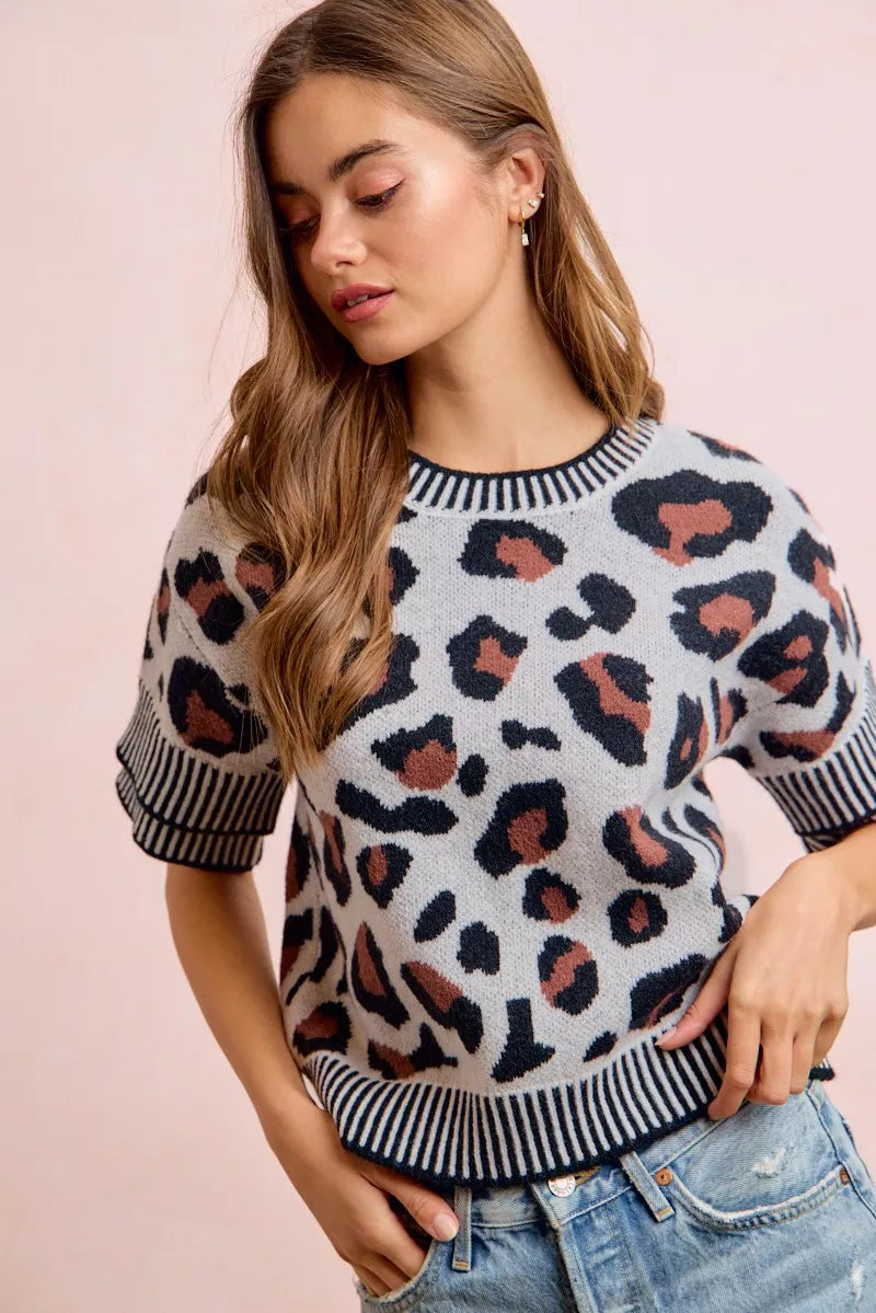 Two-tone leopard print knit top with ribbed crew neck and striped cuffs
