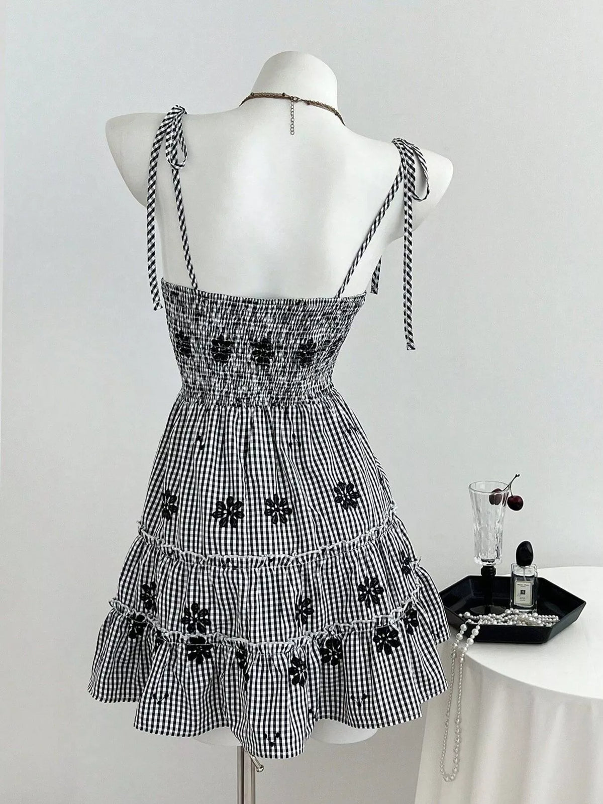 Back view: black gingham tiered mini dress with tie shoulder straps and ruffle skirt