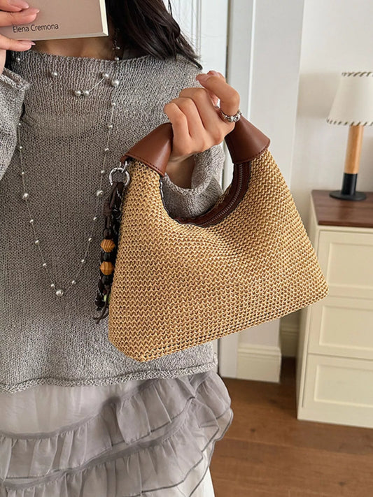 Straw crossbody bag with brown leather handles and adjustable shoulder strap, woven texture