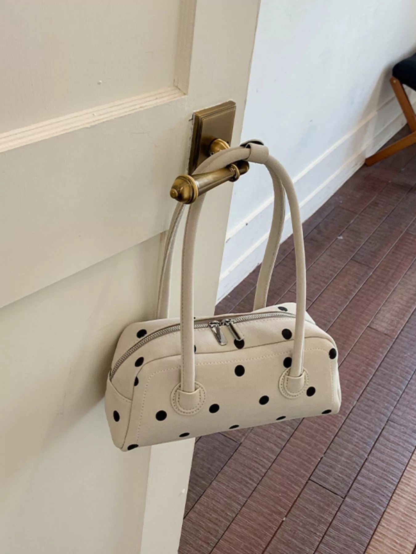 Off-white polka dot shoulder bag with zip top, top handles, and side button details