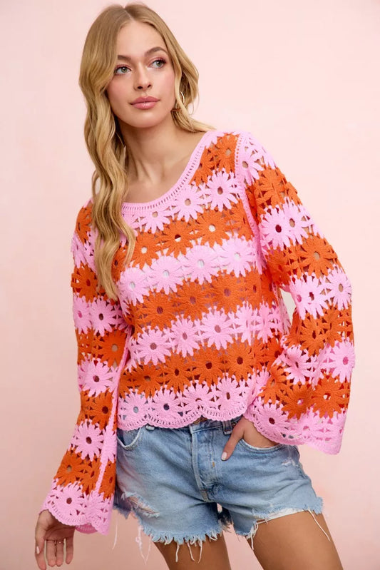 Orange crochet knit top with white daisy motifs, pink scalloped hem, long sleeves.