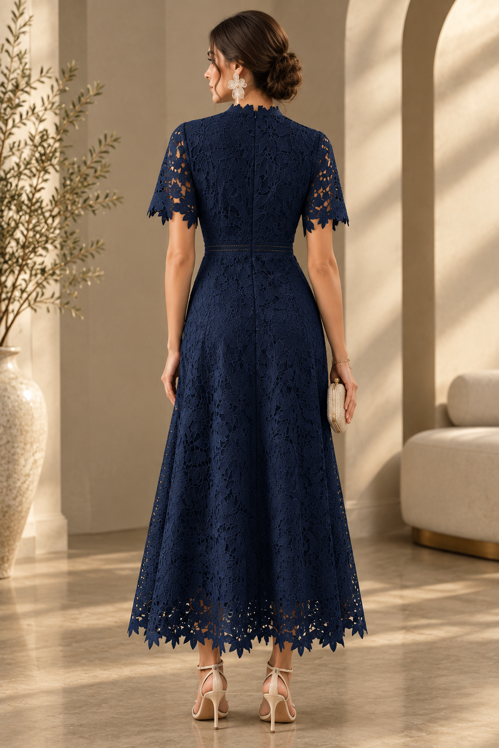 Back view of the navy floral embroidered lace dress with short scalloped sleeves, a defined waist and scalloped hem.