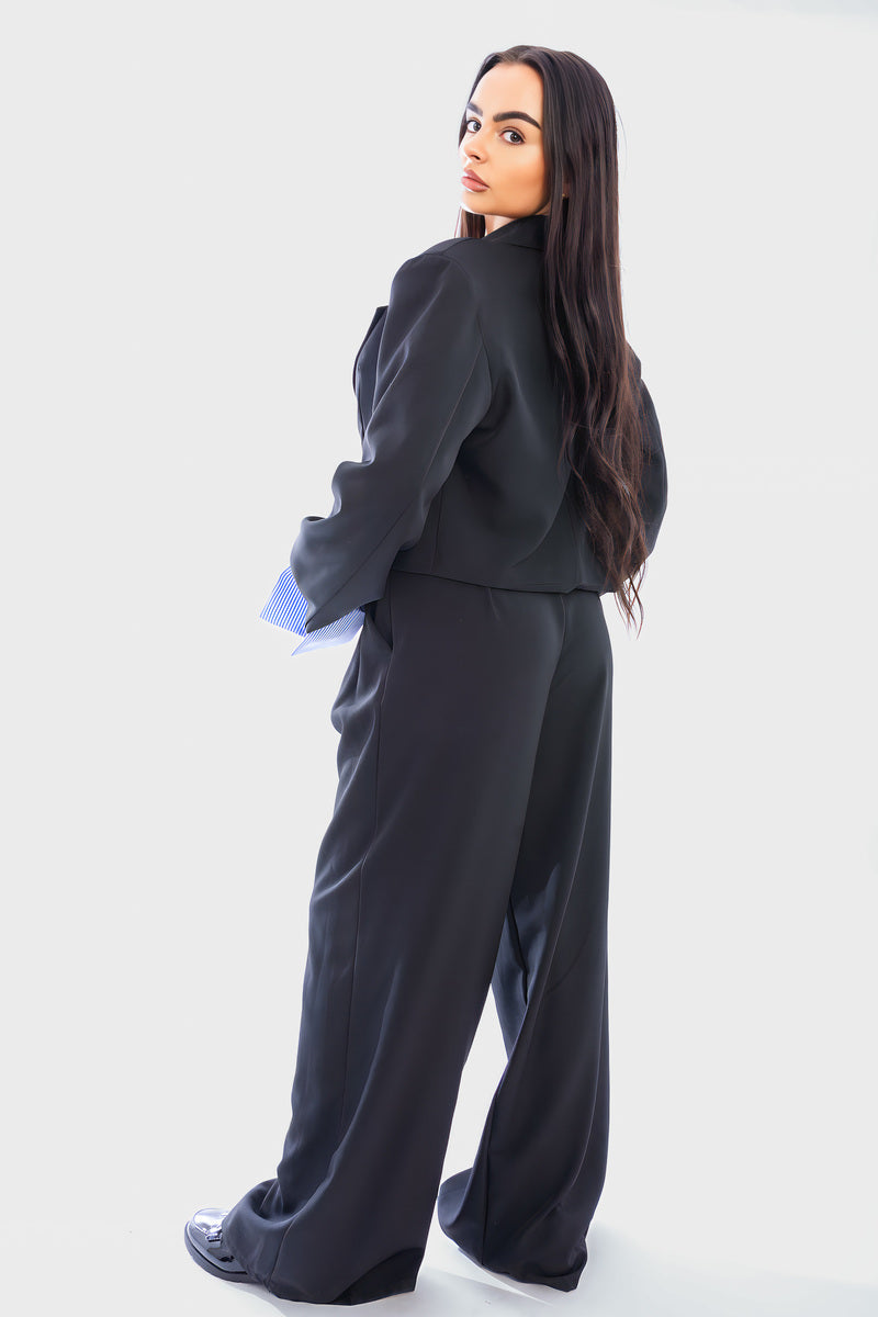 Black cropped blazer and straight-leg trousers, side view, light blue striped cuffs