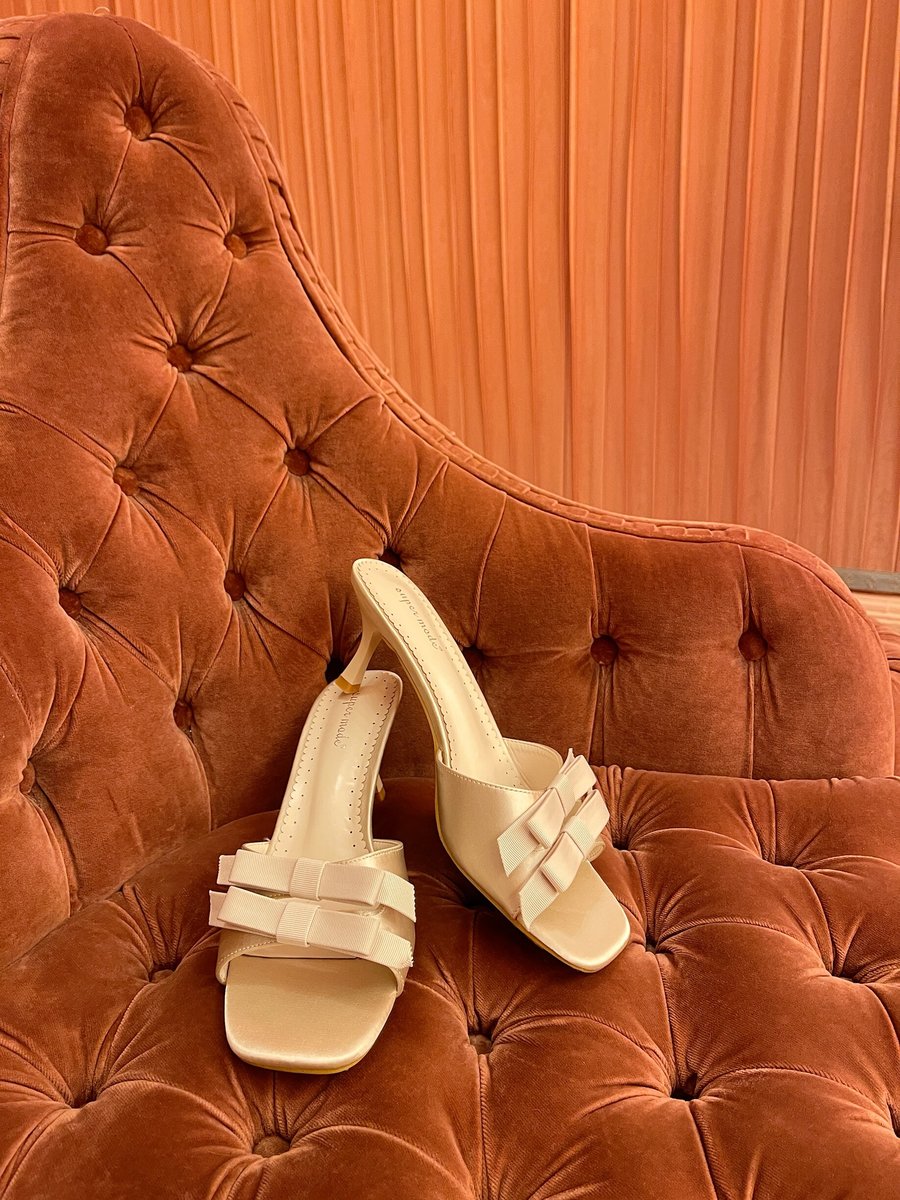 Cream open-toe high heels with bow detail on front straps, close-up