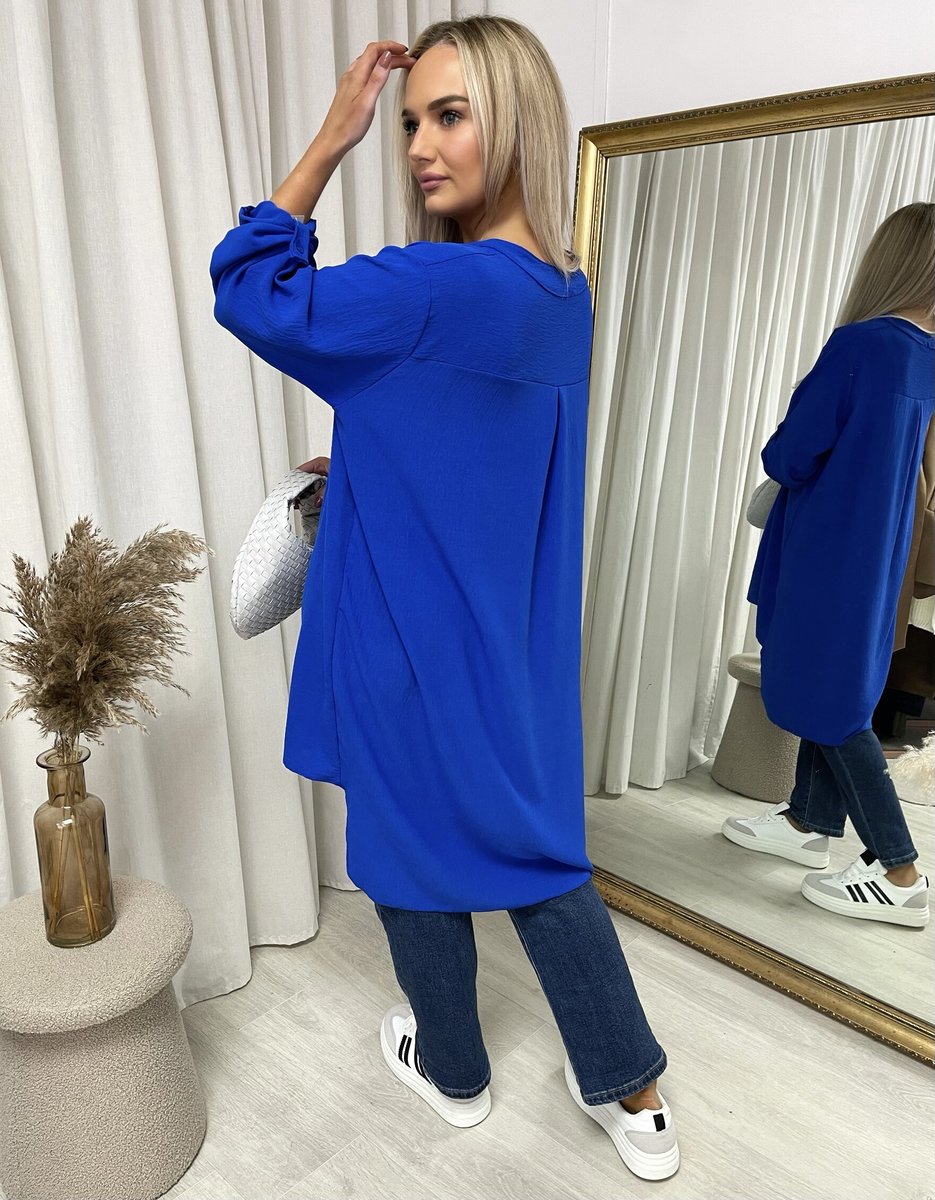 Loose-fit long-sleeve top in royal blue with roll-up sleeves, shown from the back