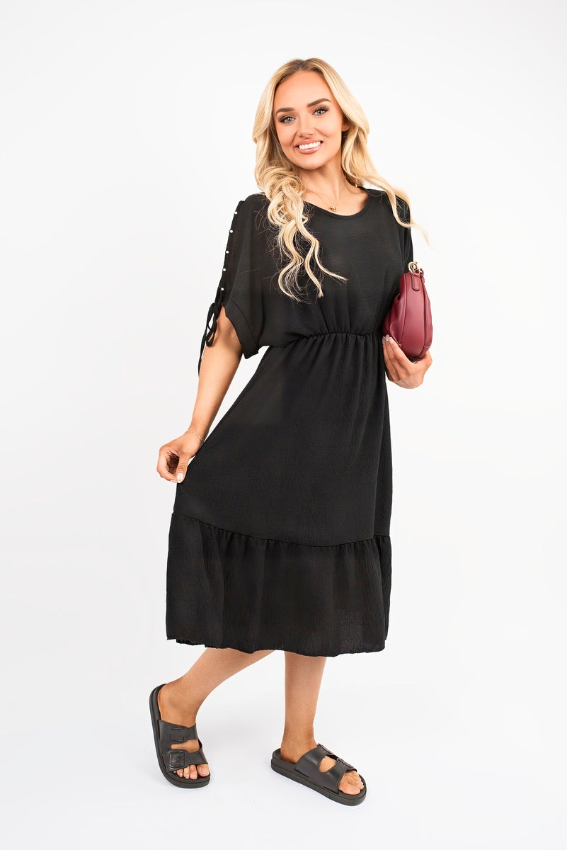Black round neck midi dress with short sleeves and tie cuff detail, relaxed tiered skirt
