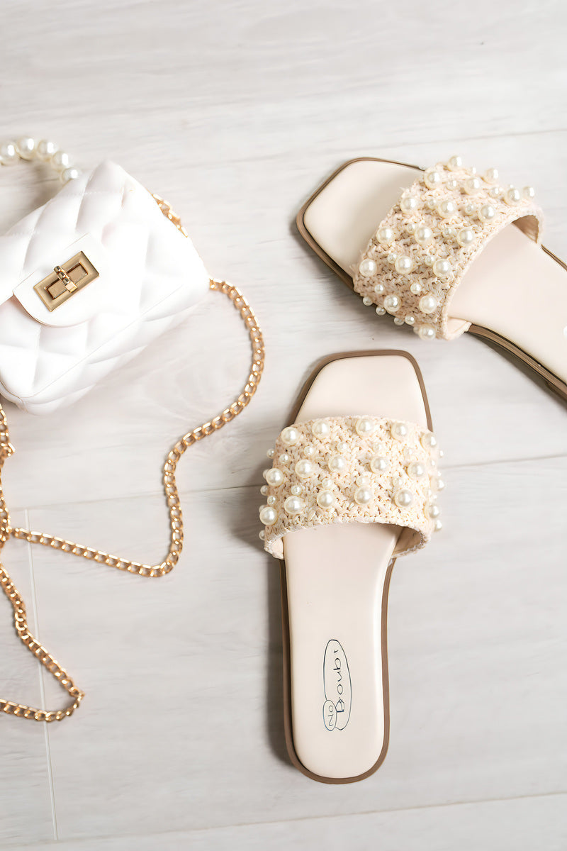 Cream open-toe flat sandals with pearl-embellished bands and slide design