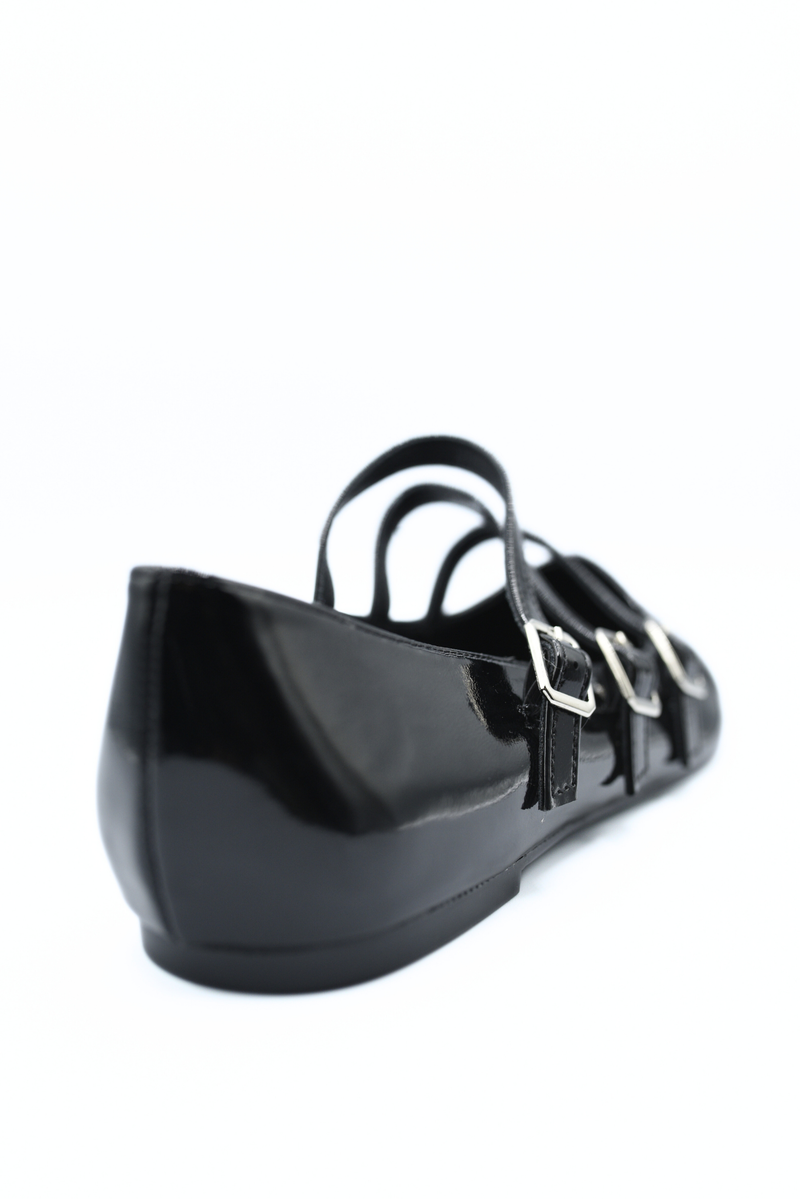 Black strappy flat shoes close-up with buckle straps and glossy finish