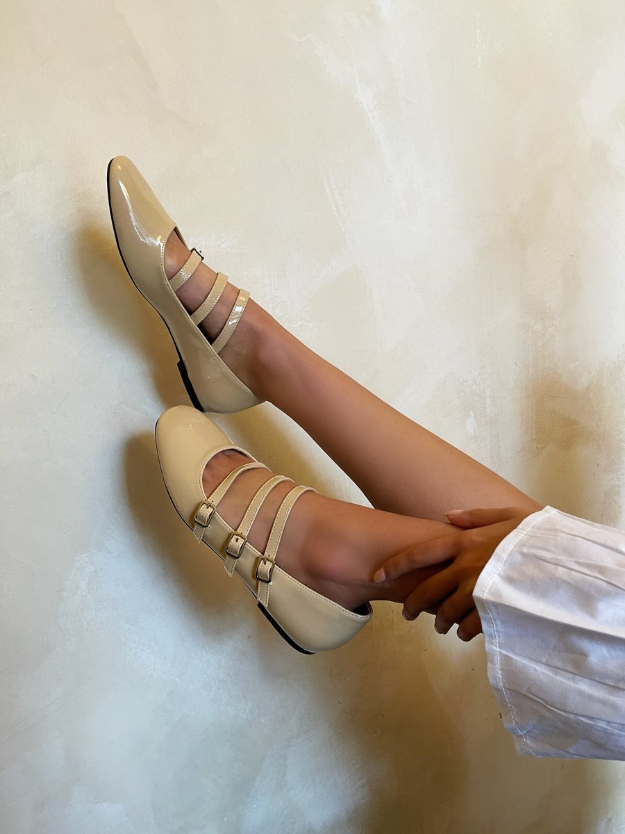 Beige strappy flat shoes with buckle straps and smooth finish, worn by model