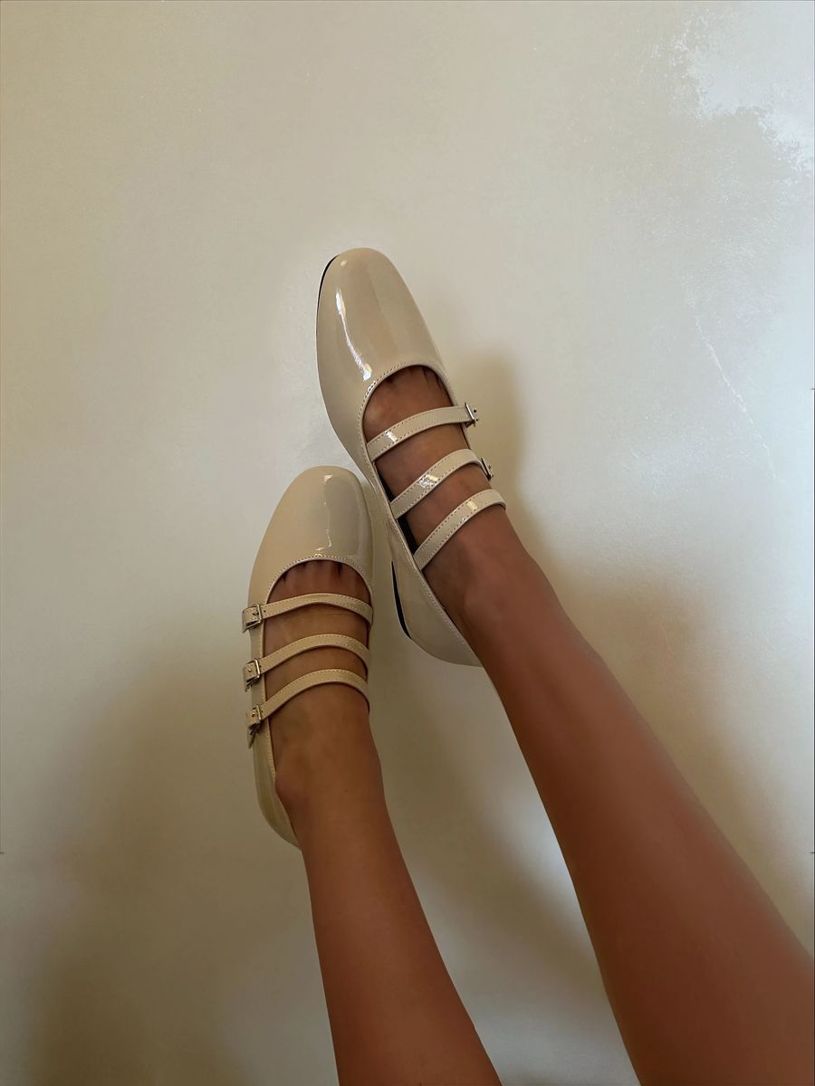 Beige strappy flat shoes with three buckle straps and smooth finish, on model