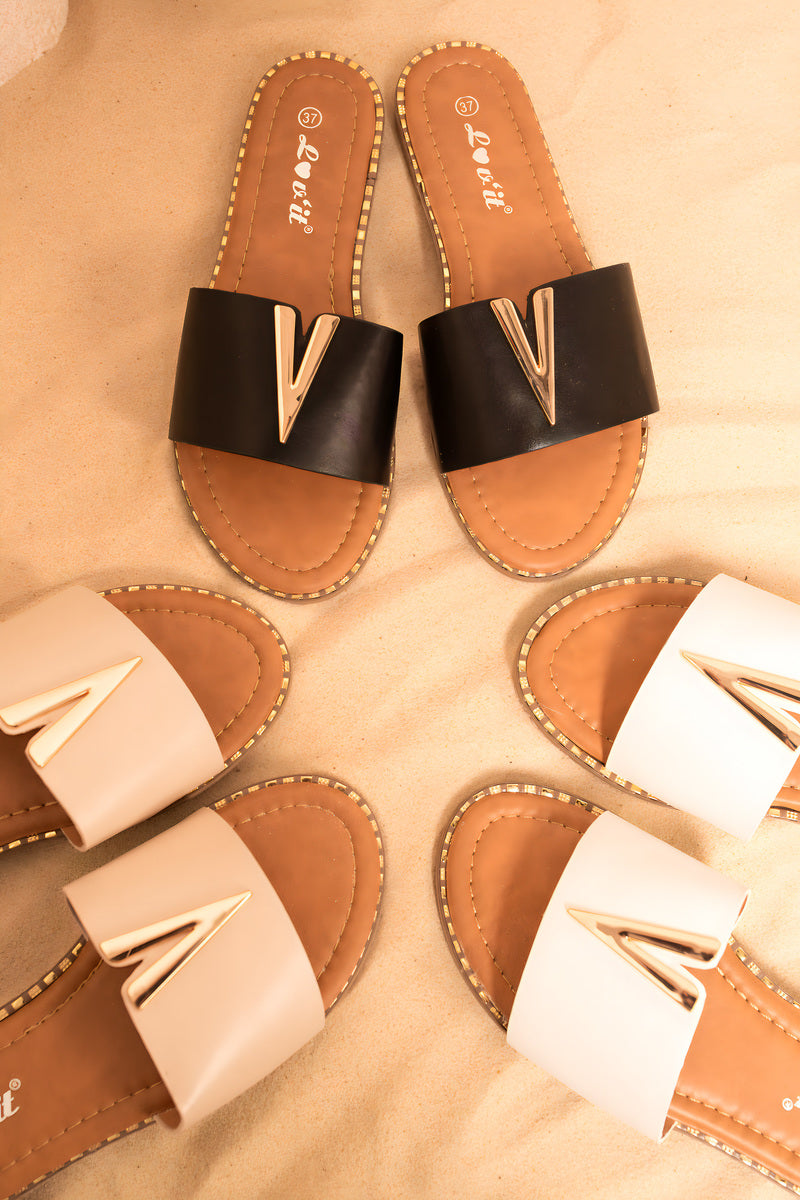 Flat lay of V-detail slip-on flat sandals: black and white pairs with gold V