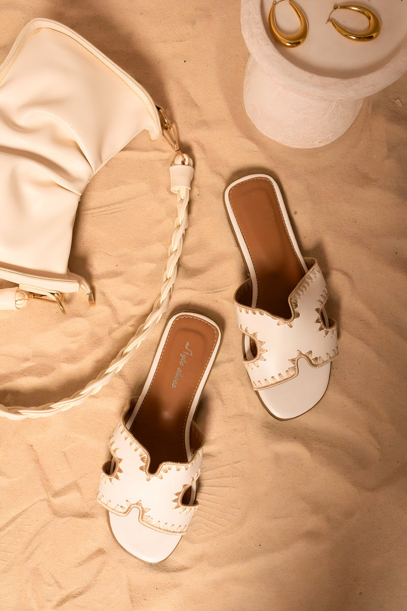 White flat slip-on sandals with cut-out trim and open toe, brown interior