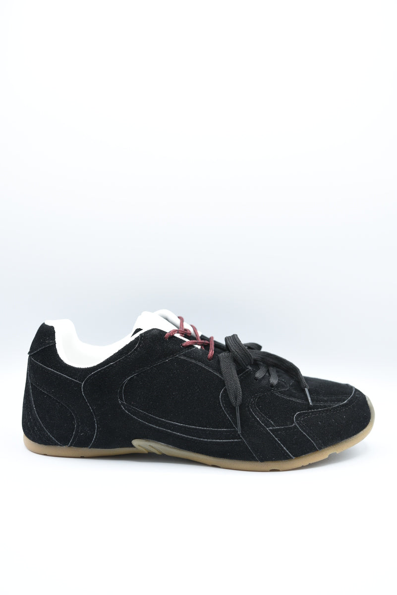 Black lace-up flat trainers with white tongue and red contrast laces, tan sole.