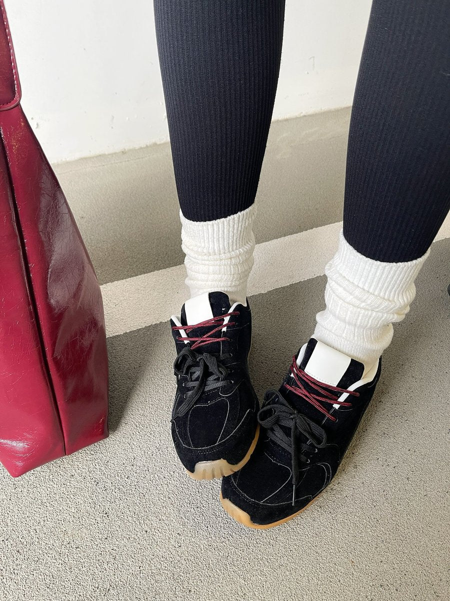 Black lace-up flat trainers with red-and-white laces and light gum sole