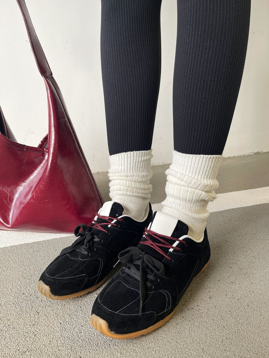 Black lace-up flat trainers with red laces and light gum sole, side view