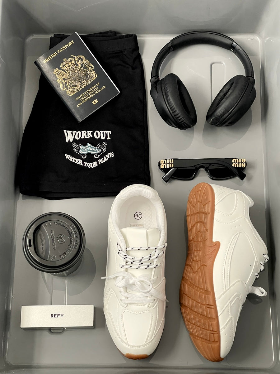 White lace-up flat trainers with tan-brown textured outsole and perforated toe.