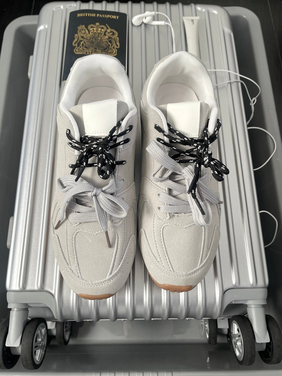 White lace-up flat trainers with black contrast laces and beige rubber sole