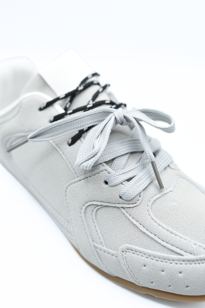 Light grey lace-up flat trainers close-up with grey laces and side stitching