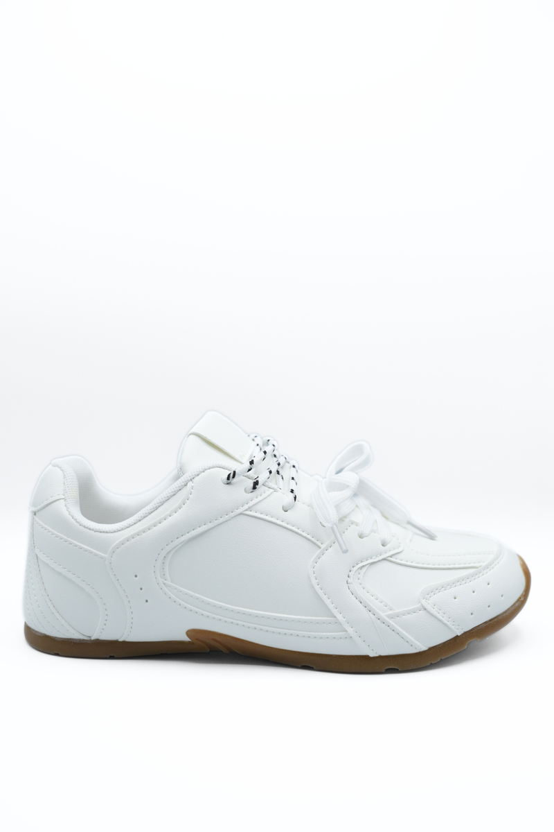 White lace-up flat trainers with side panel stitching and tan rubber outsole.