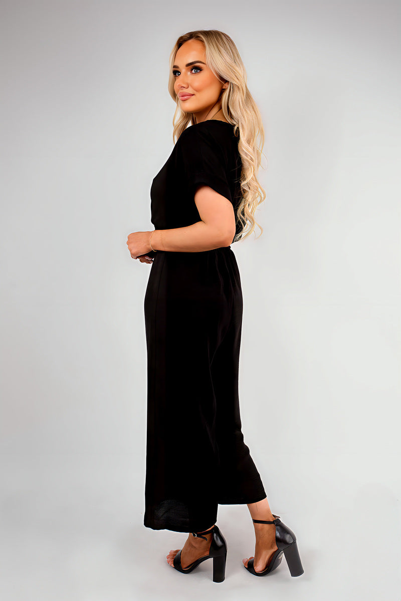 Black wrap V-neck jumpsuit with tie waist, short sleeves and wide-leg trousers