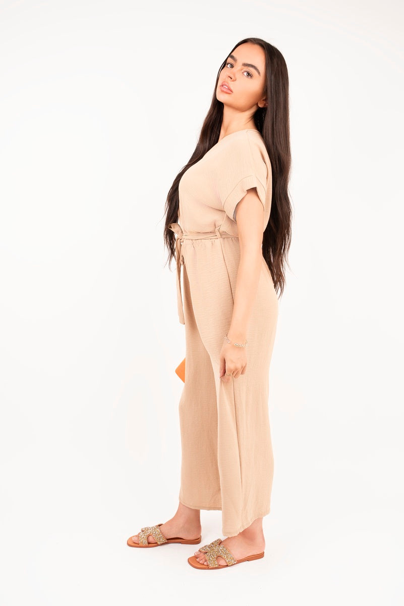 Beige wrap short-sleeve wide-leg jumpsuit with tie waist, side profile view.