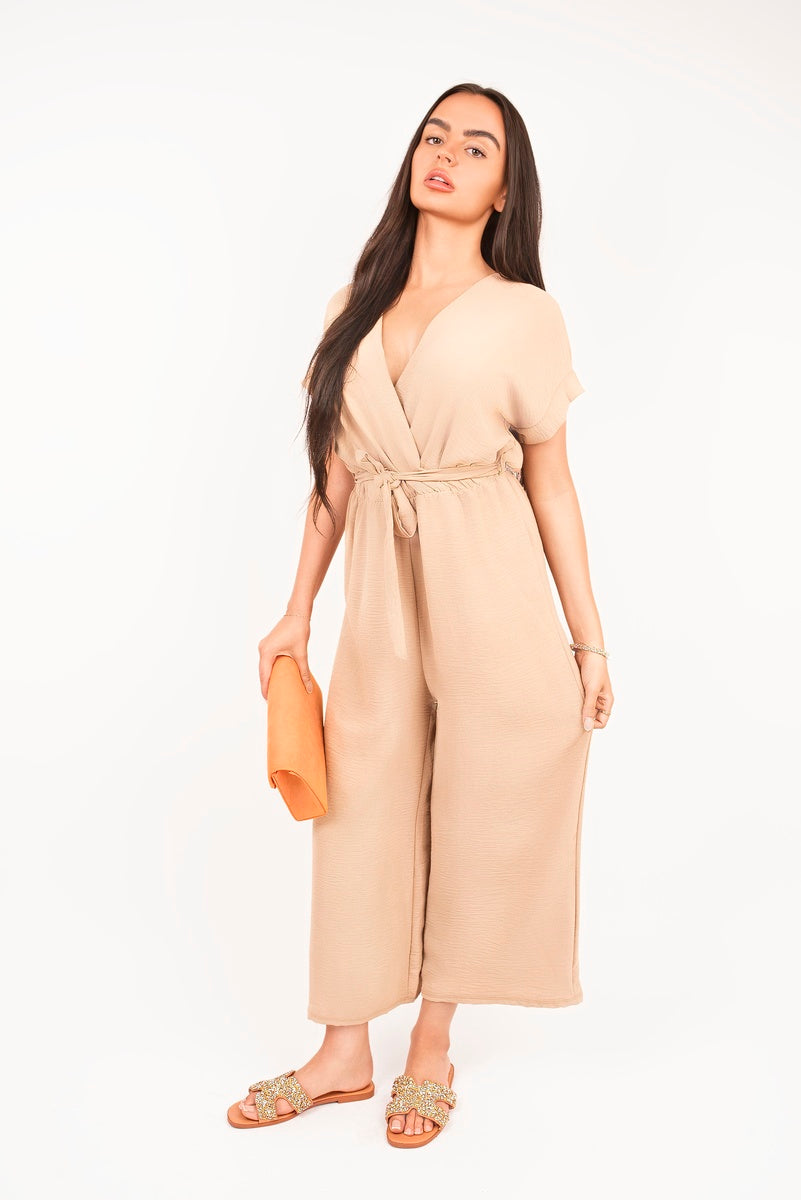 Beige wrap short-sleeve wide-leg jumpsuit with tie waist, full length standing view.