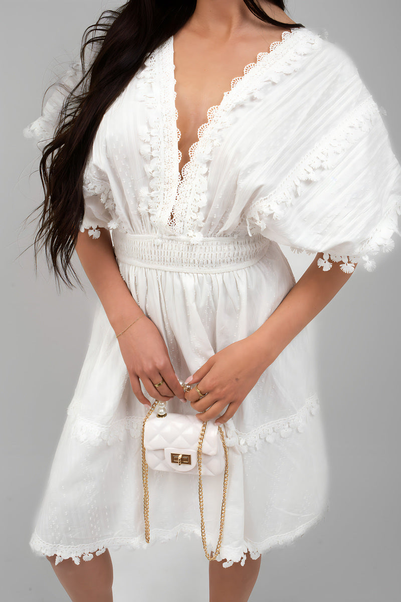 White mini dress close-up: deep V-neck with lace trim and short puff sleeves